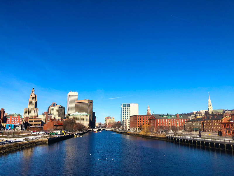 View of Providence, Rhode Island, with city buildings and a canal against a bright blue sky