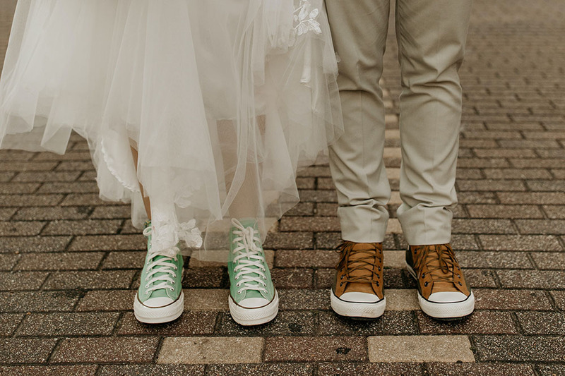 Close up photo of bride and groom wearing tennis shoes