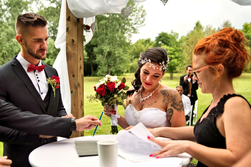 Newlyweds sign a marriage license outdoors with their wedding officiant