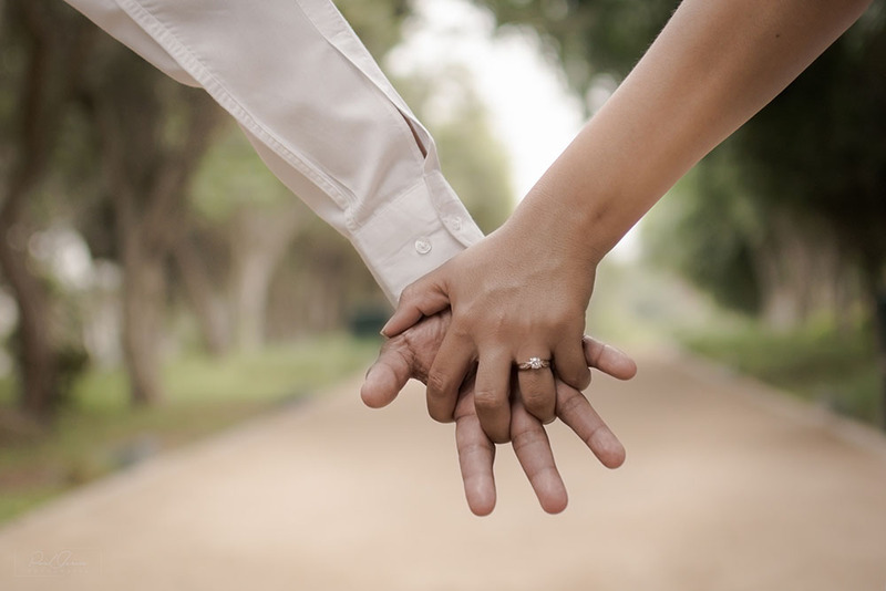 Close up of groom and bride holding hands outdoors on the wedding day