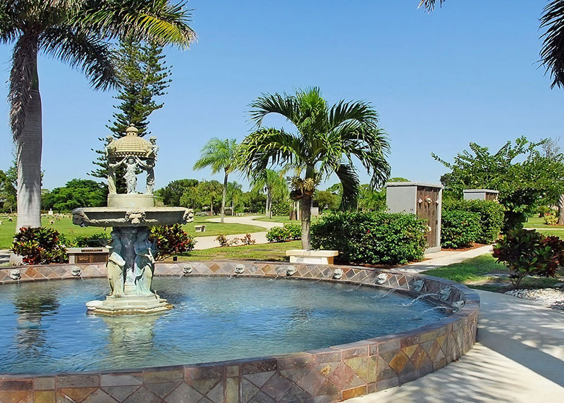 Fountain at Hodges Funeral Home in Naples, Florida, decorative fountain with water and palm trees in the distance