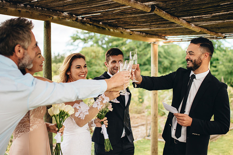 Wedding officiant gives a toast outdoors after a wedding ceremony to the bride and groom