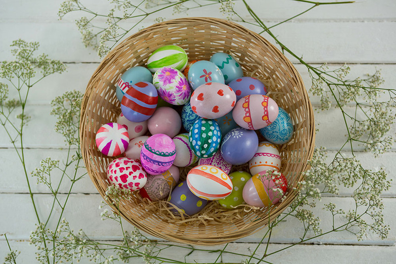 A basket of colorful easter eggs on a table next to baby's breath for a wedding or vow renewal celebration