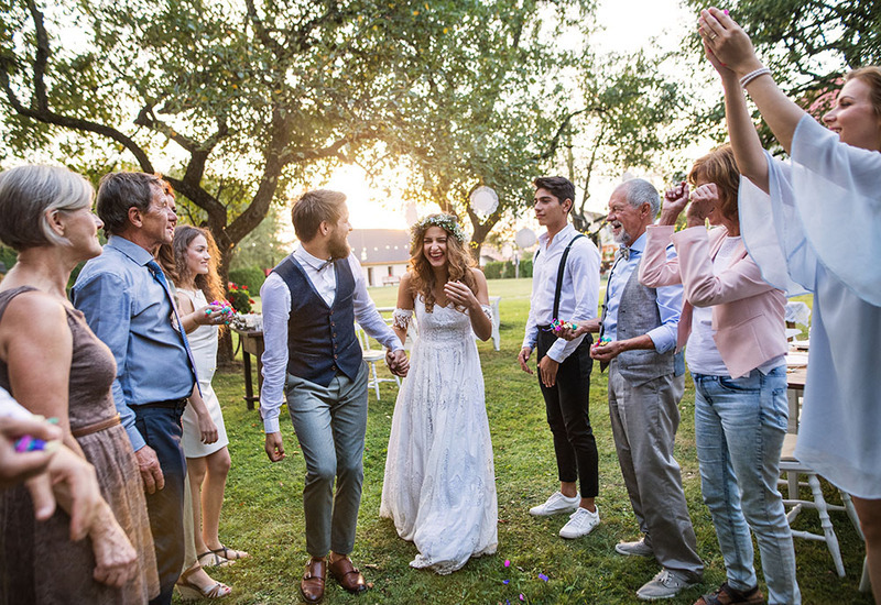 Newlyweds stand outside on a spring day with friends and relatives to celebrate their wedding ceremony