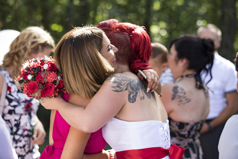 Bride hugs wedding guest after ceremony outdoors on a sunny day