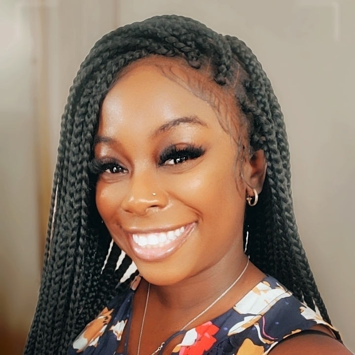 Latrice Roman wedding officiant headshot, Latrice is smiling toward the camera with her hair in braids, wearing a floral print shirt