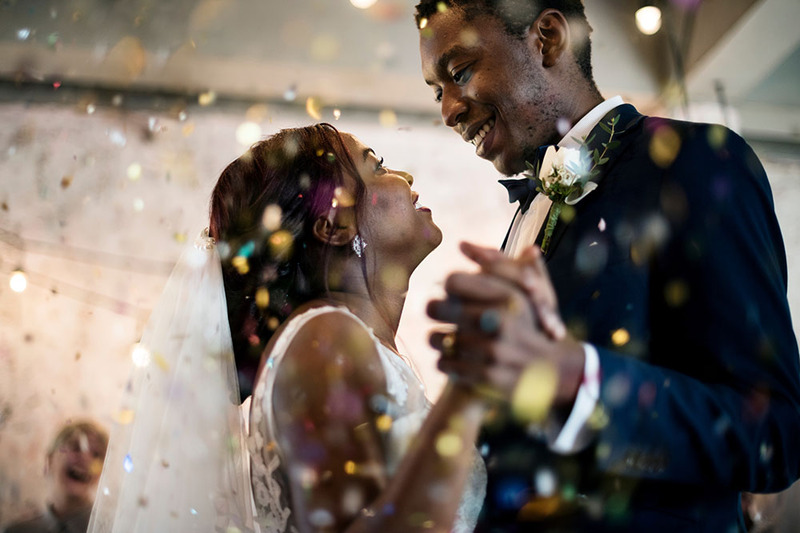 Newlyweds dance after the wedding ceremony as colorful confetti falls around them in celebration, a dreamy image of love and joy 