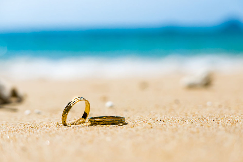 Wedding rings in the sand on a beautiful white sand beach.