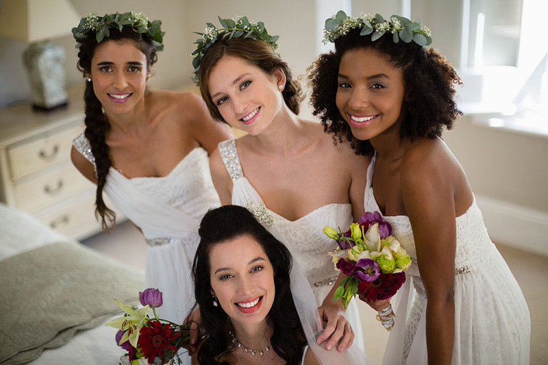 Bridesmaids smile at the camera, posing with the happy bride on the wedding day.