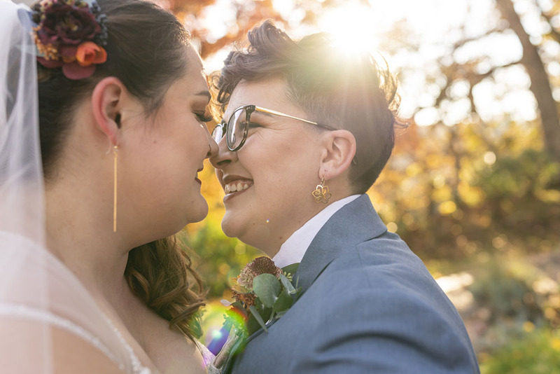 Two brides lean together for a kiss during their wedding ceremony