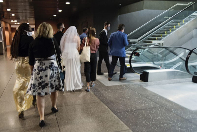 Friends and relatives walk with a bride and groom leaving a courthouse wedding ceremony civil marriage