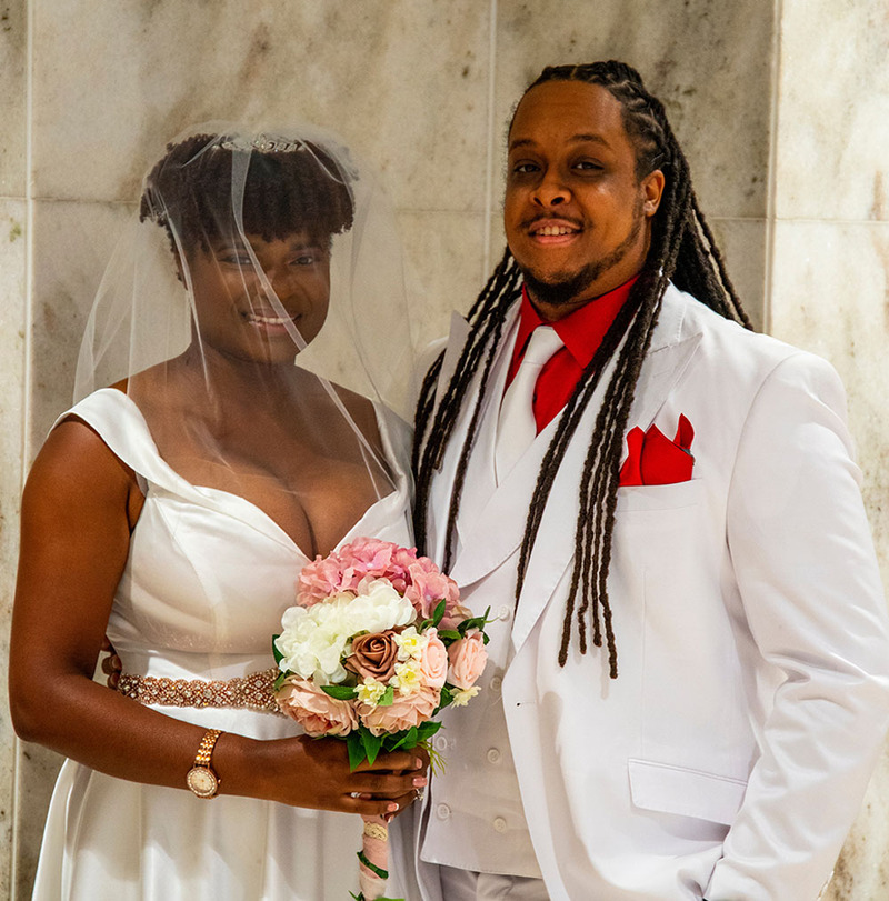 Bride and groom pose for a photo on their wedding day, smiling and happy