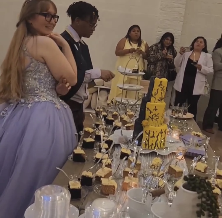 Brides Laura and Beka pose next to a dessert table featuring cookies and cake baked by officiant Chef Toni Lawson of Tesserts 