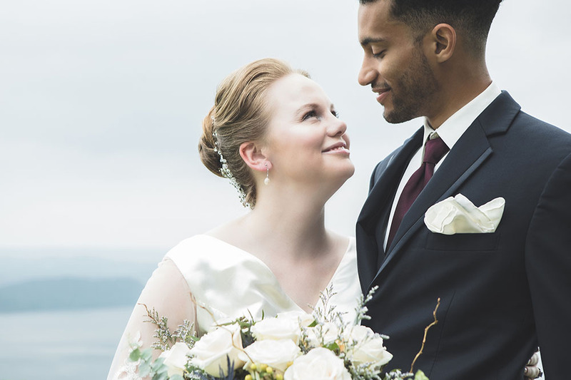 Interracial bride and groom pose on the wedding day, smiling at each other 