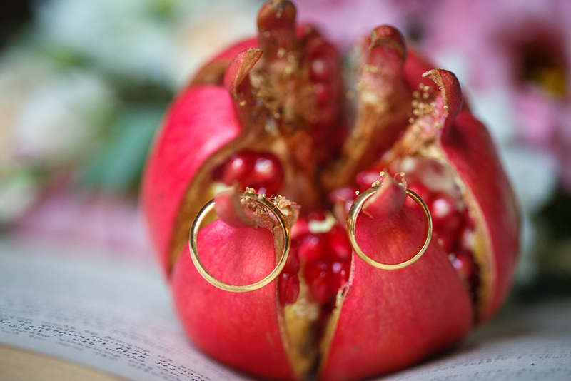 Red pomegranate with wedding rings