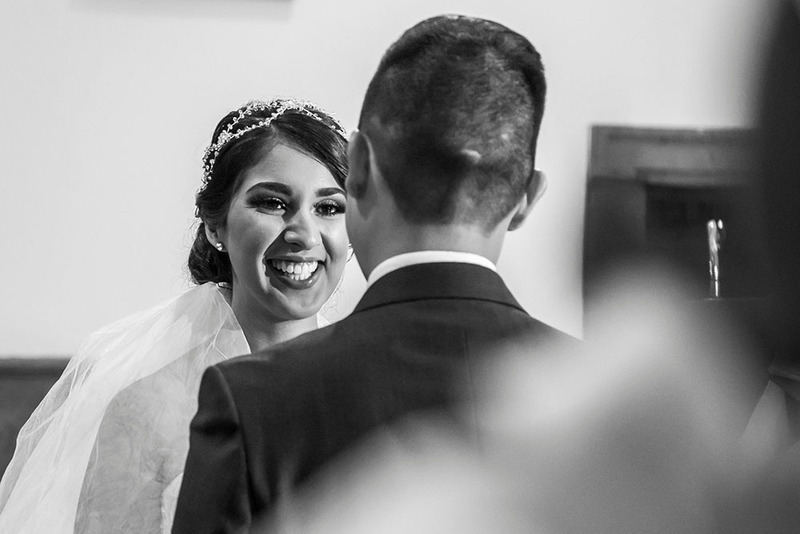 Bride looks lovingly at groom, who is standing in front of her facing away from the camera