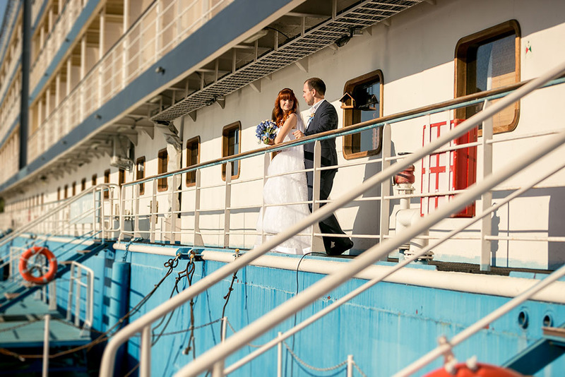 Bride and groom pose in their wedding attire on the deck of a cruise ship