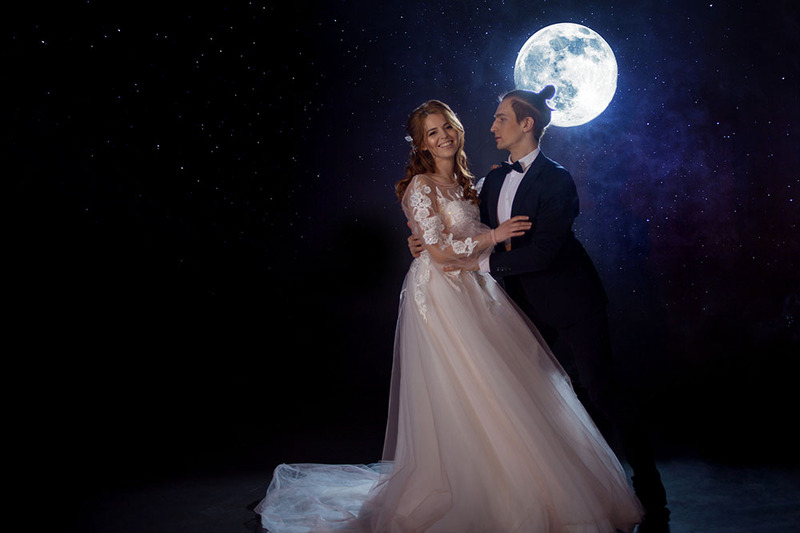 bride and groom smile in front of a full moon on their wedding day