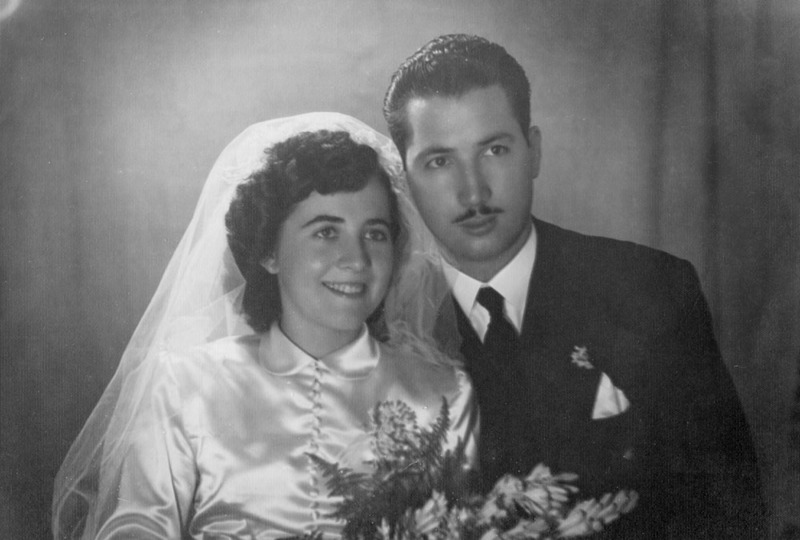 Vintage wedding photo from the 1940s shows a bride smiling and a groom with a somber expression