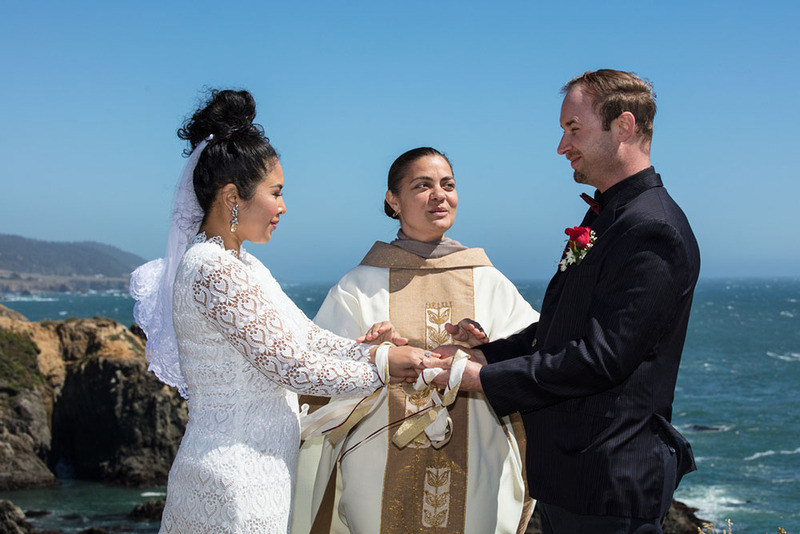 A wedding officiant performs and outdoor ceremony for a bride and groom