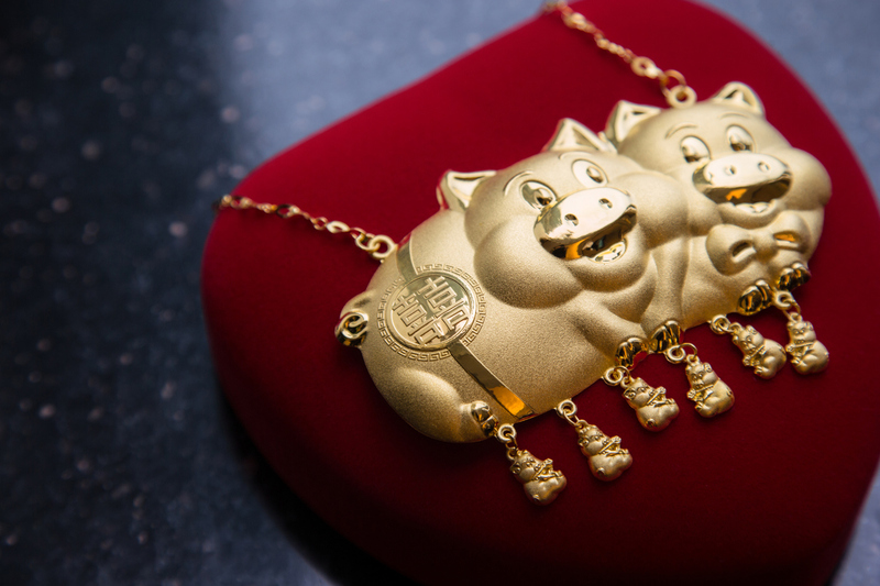 Photo of a Chinese gold pig necklace for wedding celebration, there are two large pigs, with smaller dangling piglet charms