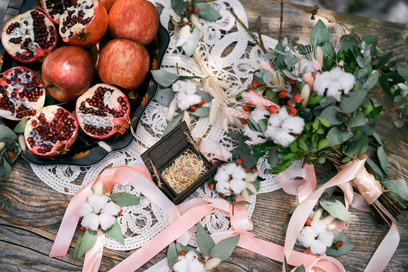Close up of a wedding table or wedding altar, with pomegranate fruits, apples, wedding rings, and other winter wedding theme items