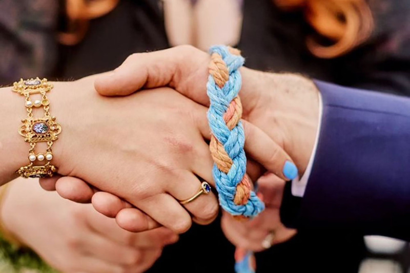 Close up of a handfasting cord tied around a couples hands during a handfasting ceremony
