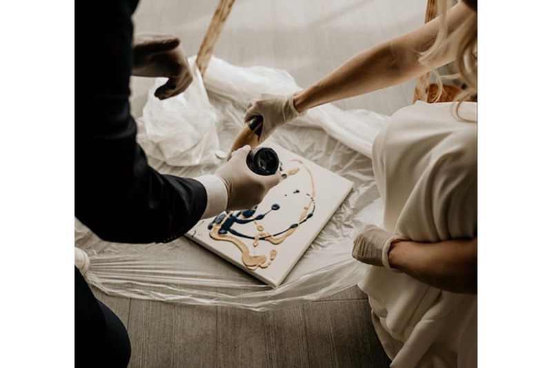 Close up photo of a couple creating a unity painting during their wedding ceremony