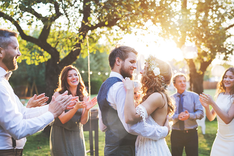 Newlyweds dance outside after the wedding ceremony while friends and relatives watch happily