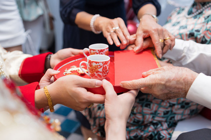 Close up photo shows parents handing the bride and groom red envelopes as gifts during the Chinese tea ceremony wedding tradition