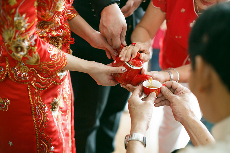 Close up of a bride pouring tea for her parents or grandparents during a traditional Chinese tea ceremony wedding ritual