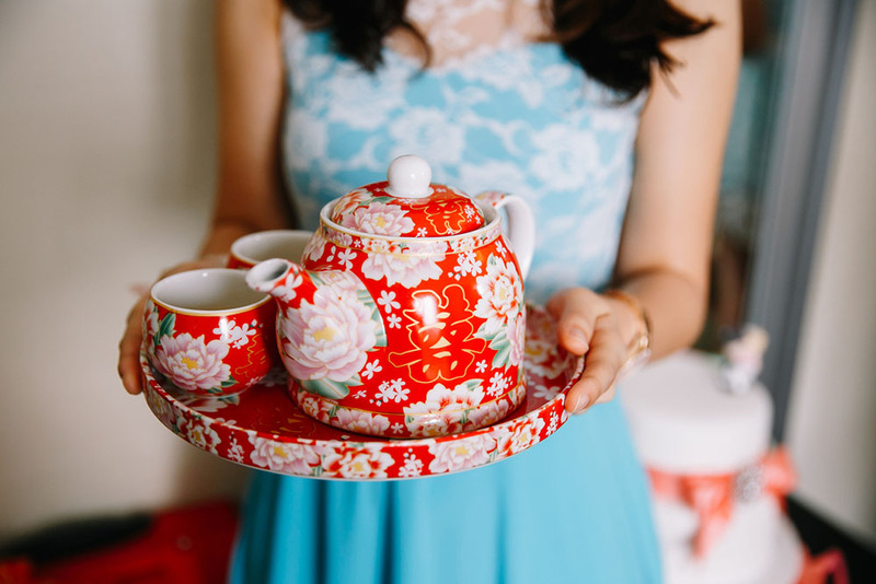 Close up of a woman in blue wedding dress holding a Chinese wedding tea set