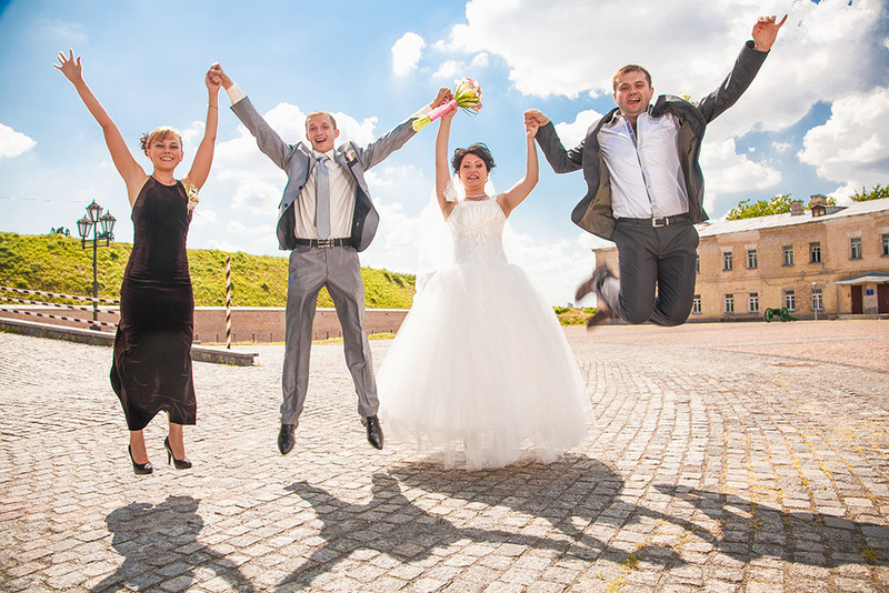 Bride and groom jump in the air happily with two friends while eloping