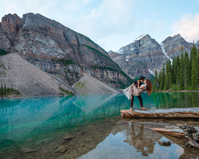 Young couple embrace on the side of a mountain lake 