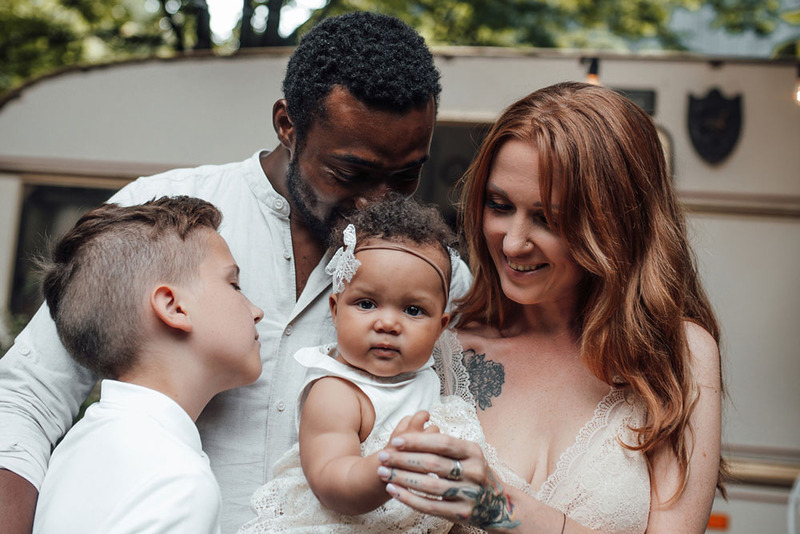 Young family elopement photo, the husband and wife stand with two young children in a loving and happy pose