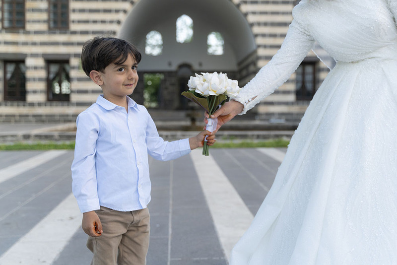 Close up of a young boy holding wedding bouquet with his mom the bride