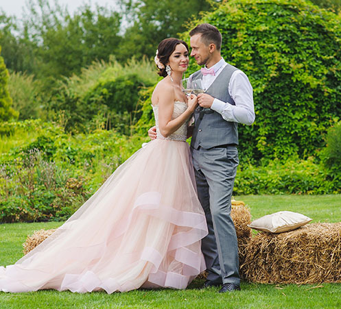 bride in pink wedding dress poses outside with groom on wedding day