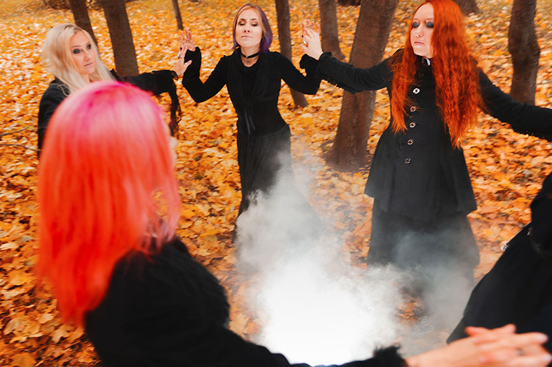 A coven of witches perform a ceremony in the woods