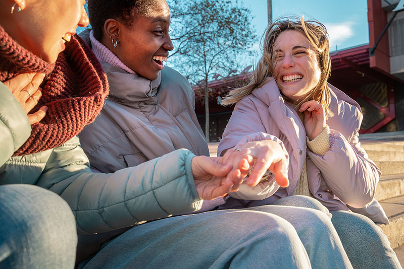 A woman shows off her engagement ring to friends