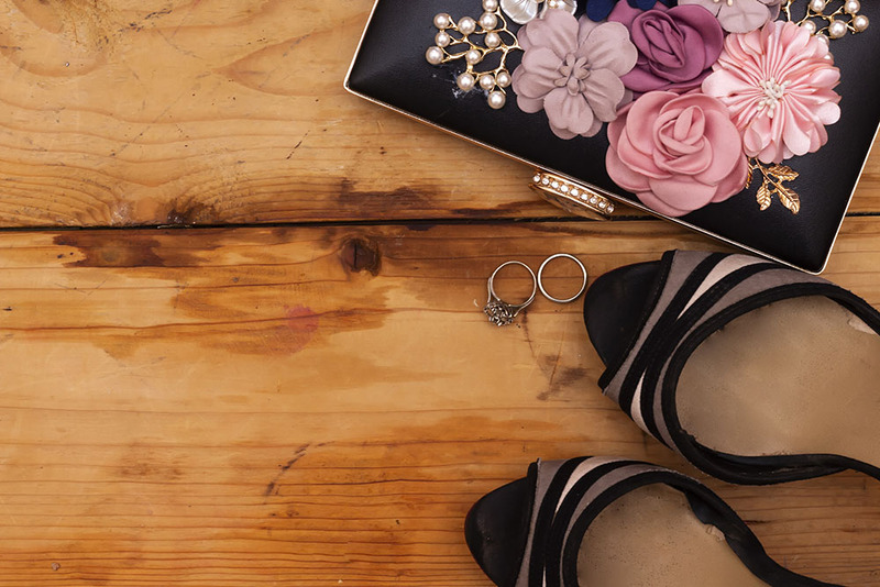 Close up of black heels, floral purse, wedding rings
