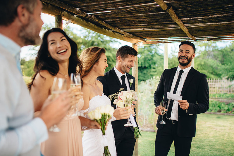 Newlyweds listen as a friend toasts them at the wedding reception