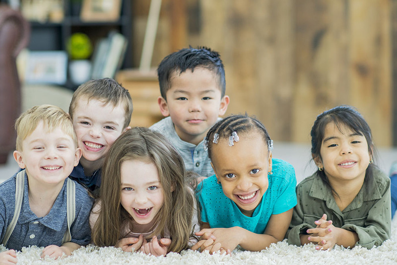 A group of young kids laying together smiling at the camera