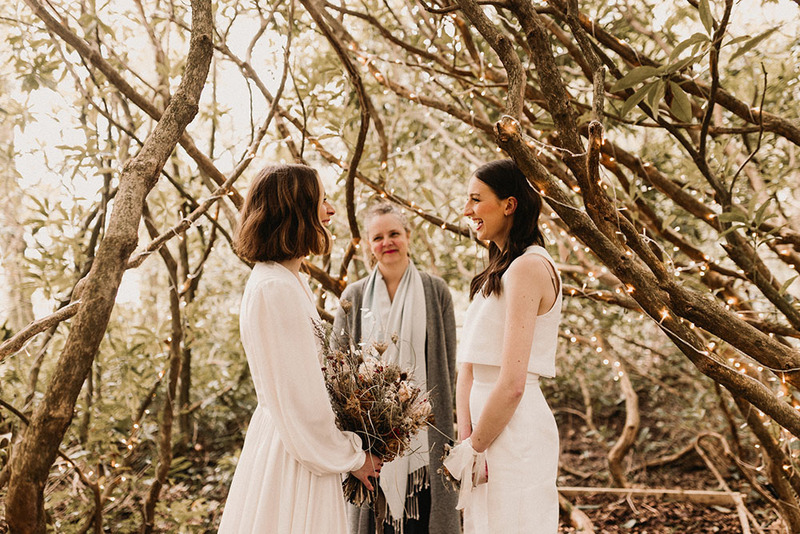 Two brides exchange wedding vows during a wedding in a forest