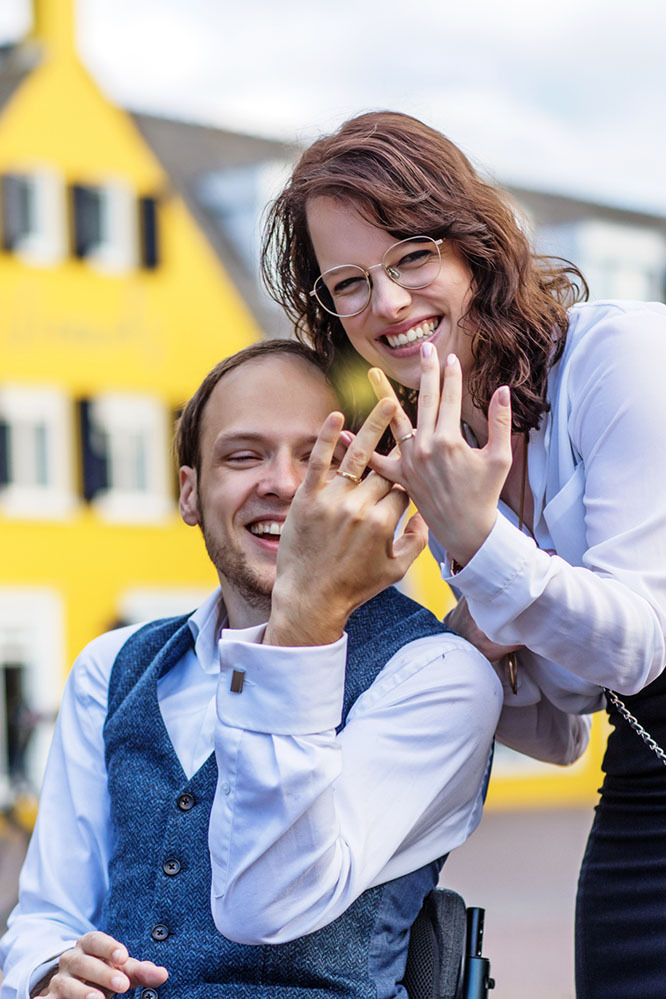 Young newlyweds hold up their wedding rings to show them off happily on the wedding day
