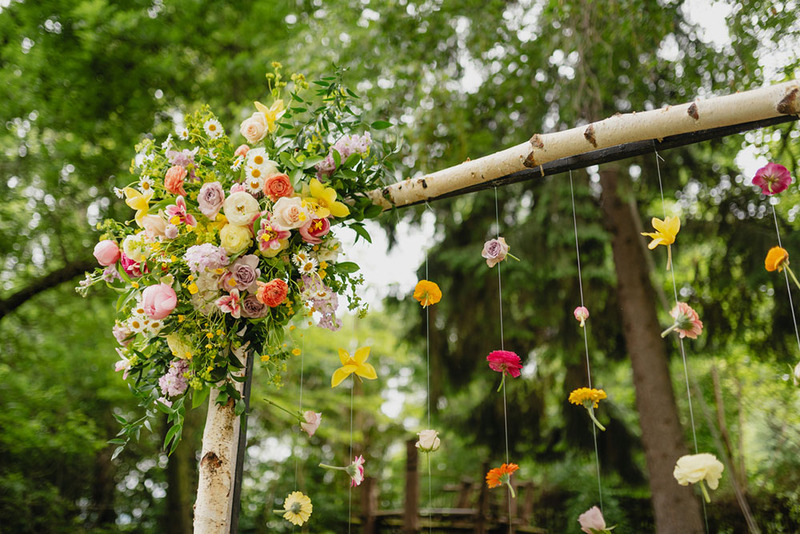 Lush summer wedding arch decorated with flowers and greenery, a beautiful green forest in the background