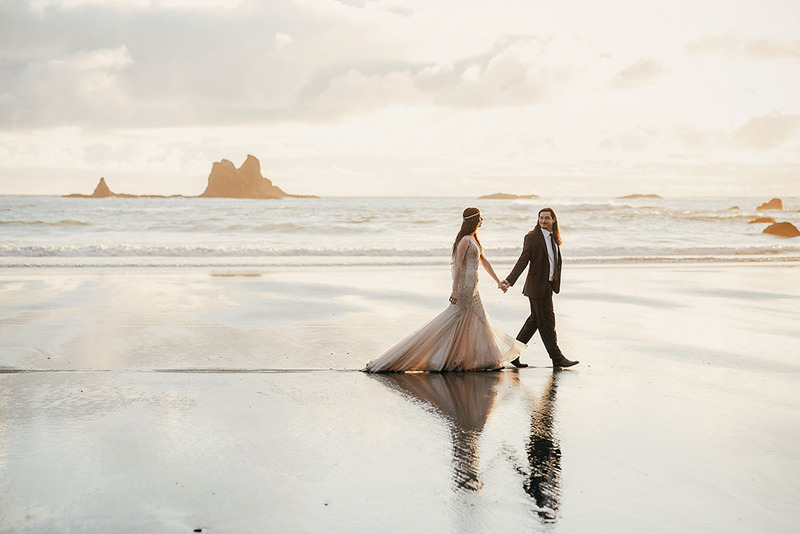 Los novios caminan por una playa de Oregón el día de la boda