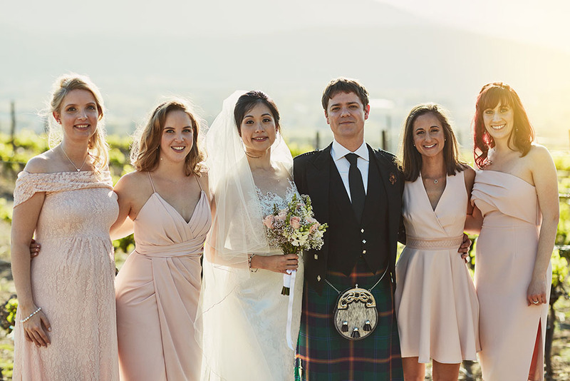 Bride and groom pose with bridesmaids during a scottish wedding outdoors