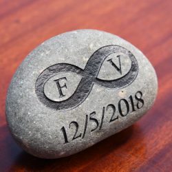 A wedding oath stone used in the oathing stone ceremony, carved with the initials F and V, an infinity symbol, and the wedding date