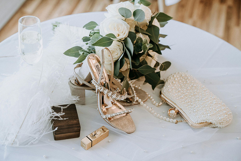Photo of a bridal clutch and shoes arranged on a table at the wedding