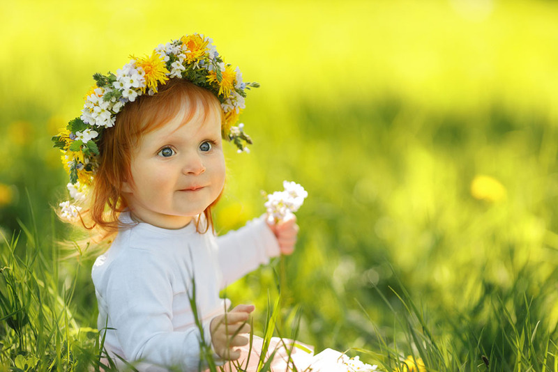 a young girl with red hair wears a wreath of dandelions and clover in a sunny field on the wedding day